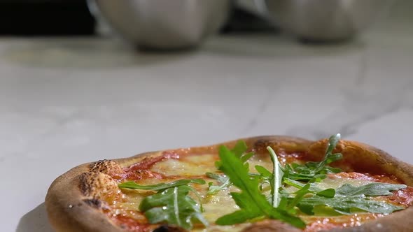 Homemade pizza. baker decorates pizza from oven with fragrant basil