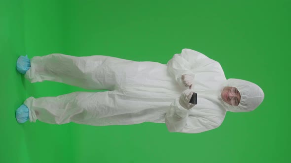 Full Body Of Asian Man Wear Protective Uniform Ppe And Use Mobile Phone In The Green Screen Studio alt
