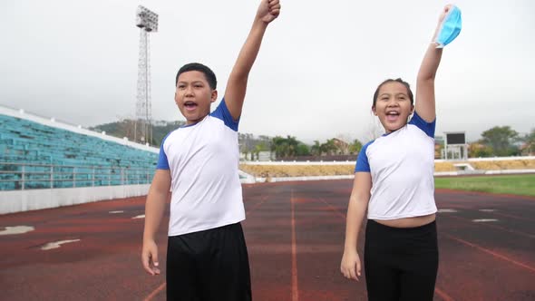Happy Asian Boy And Girl Takes Off Mask And Running At Stadium  alt