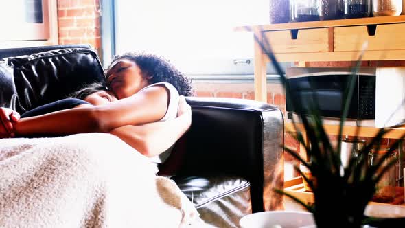Lesbian couple sleeping together on couch alt