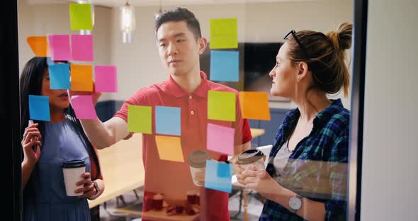 Mixed-race business people discussing over sticky notes in a modern office 4k