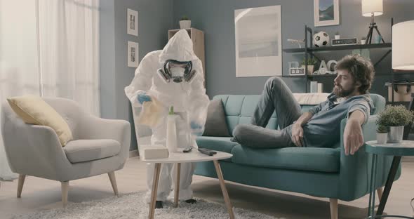Paranoid woman disinfecting her home with hazmat suit during coronavirus pandemic