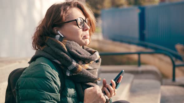 A Young Woman in Glasses Sings Along To the Music in Her Wireless Earphones alt