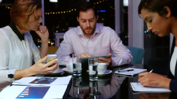 Businessman discussing work on digital tablet with colleagues alt