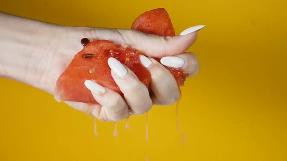 Close-up, a Slice of Ripe Watermelon Is Squeezed in Hand, Juice Is Coming. Watermelon Pulp Is
