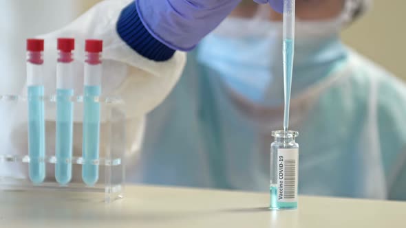 Professional Female Scientist in Protective Eyeglasses and Mask Making Experiment with Reagents in alt