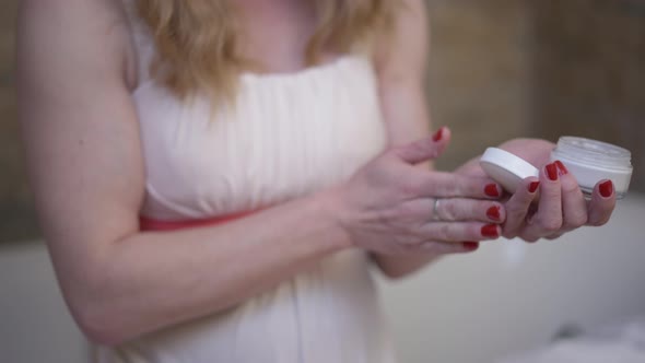 Hands of Unrecognizable LGBTQ Trans Person Applying Skin Moisturizer Indoors alt