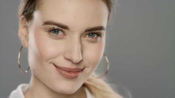 Portrait of Happy Woman Smiling and Looking in Camera on Gray Background alt
