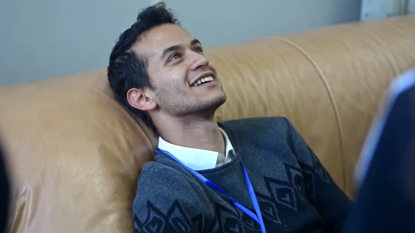 Young Male Student is Having Fun and Chatting with Friends on Couch in College Irrl alt