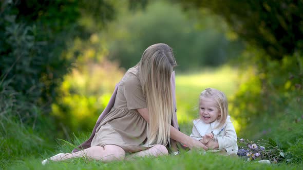 Happy young mum and baby playing together outdoor enjoy beautiful field of sunshine and spring
