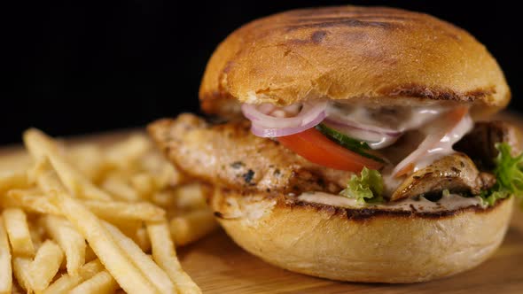 Close Up of a Grilled Chicken Burger with Bacon and French Fries alt