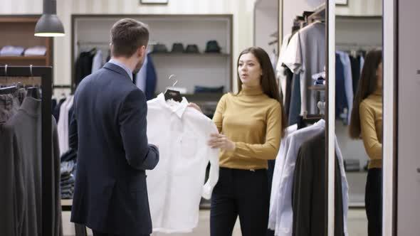 A Side View General Shot of a Clothing Boutique Consultant Proposing To a Male Customer To Check Out