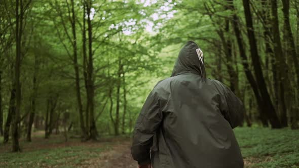 Professional Woodcutter Walking with Pro Ax in Wild Deciduous Forest. alt