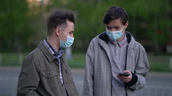 Two Friends in Medical Masks Talking When Meeting Outdoors