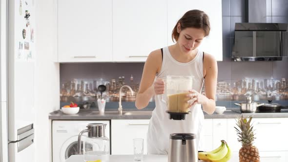 Young Attractive Caucasian Female Making Fruit Smoothie Using Blender Then Drinking It with Pleasure alt