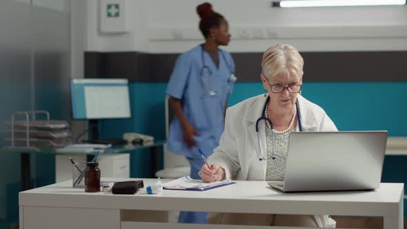 General Practitioner Working with Appointment Report on Laptop alt