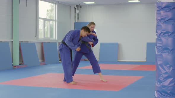 Female Jiu-Jitsu Athlete in Kimono Sparring with Male Partner alt