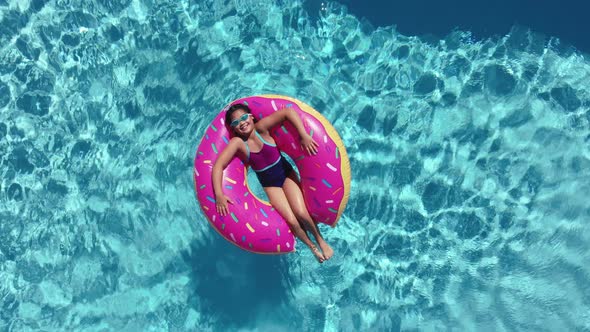 Young girl laying on inner tube in pool.