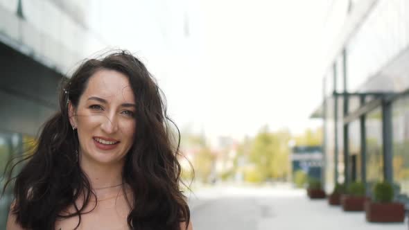 Portrait of Young Happy Woman with Curly Long Hair is Looking and Smiling