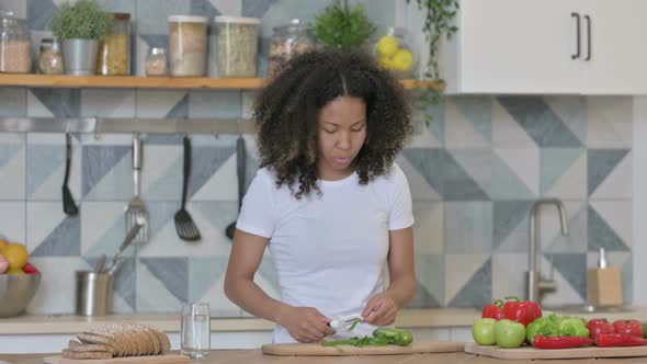 African Woman Feeling Tired While Cutting Vegetables in Kitchen alt