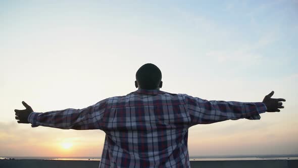 Afro-American Man Stretching Hands on Sunset Background, Inspiration, Back-View