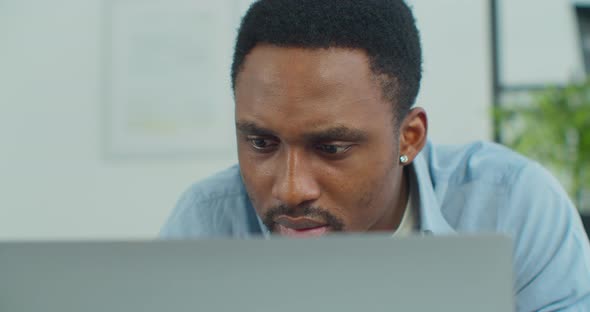 Serious Focused Young African Man Working on a Laptop From His Home Office alt
