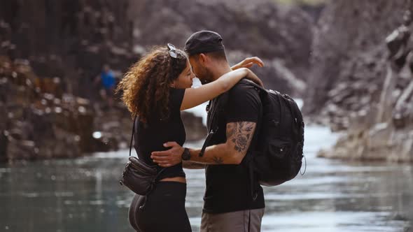 Romantic Couple Hugs with the River Along Studlagil Canyon Seen in Background alt