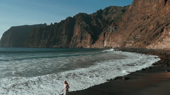 Girl Runs Along a Black Beach in a Long Dress in Los Gigantes Tenerife Canary Islands