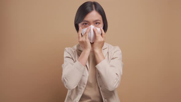 Asian business woman wearing hygienic mask for protect flu standing isolated over beige background.