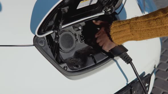 A Darkskinned Male Driver Disconnects the Electric Car From the Power System alt
