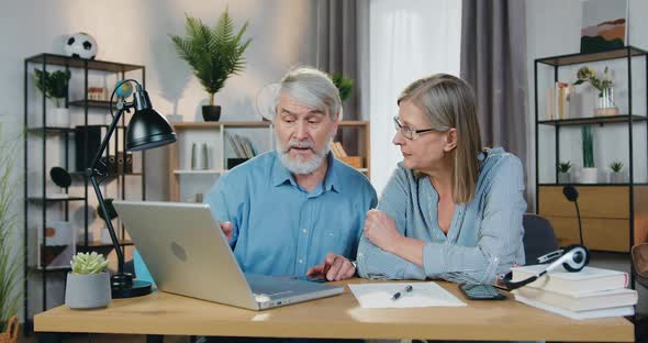 Couple Pointing on Laptop Screen and Discussing Something alt