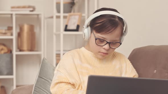 Girl with Down Syndrome Browsing on Laptop at Home alt