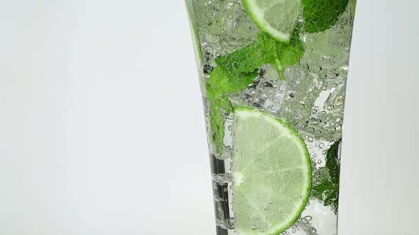 Close Up of Soda Water in Glass with Fresh Slices Lime Mint and Ice on Table Mojito Cocktail
