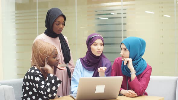 Muslim Asian and African Women in Hijabs Sit in Cafes and Make Online Purchases Using a Laptop alt