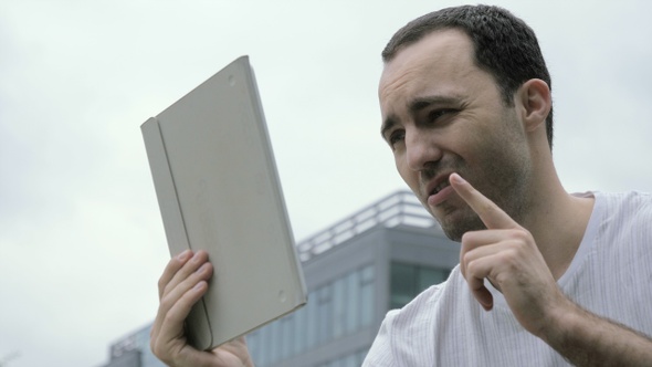 Young Handsome Man Talking to Someone Using Tablet in A alt