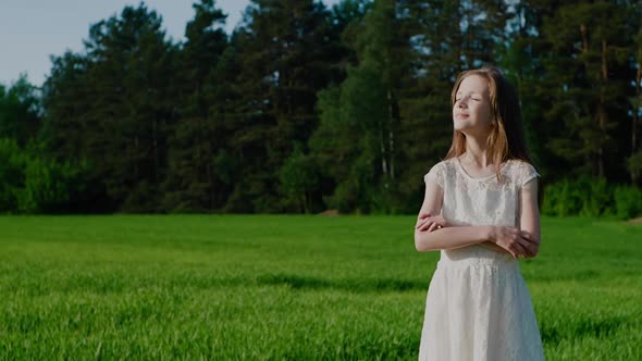 School Age Girl in White Dress Against the Background of Nature