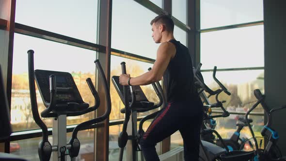 Portrait Fitness Man Warm Up Before Training on Elliptical Cross Trainer in Gym Club. Close-up Male alt