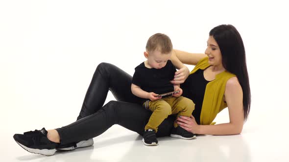 Mom and Child Are Watching Cartoons on a Smartphone. White Background alt