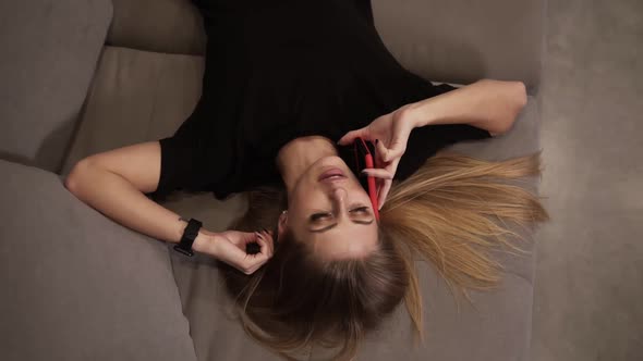 Beautiful Sexy Girl with a Mobile Phone Lies Sofa at Home alt