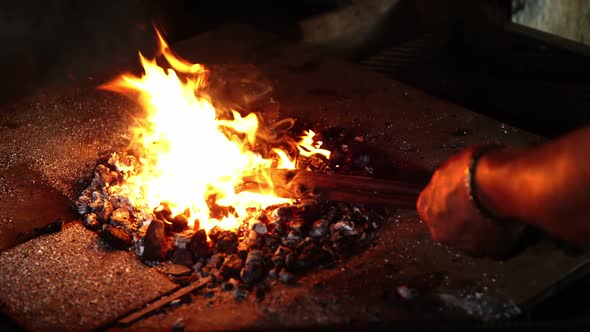 Hand of blacksmith heating a horseshoe in fire alt