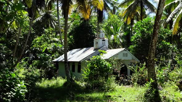 A small cute old white church chapel with cross surrounded by forest and trees on a small remote isl alt