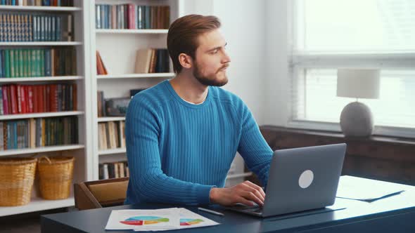 Thinking young man at home office. Young male professional using computer sitting at home office alt