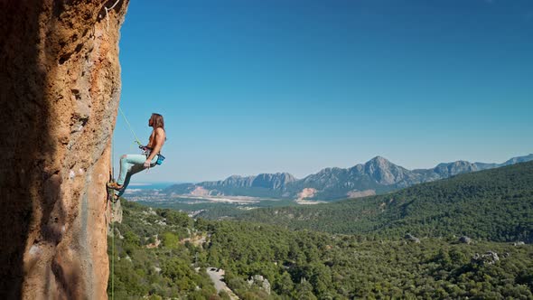 Side View of Strong Handsome Man Rock Climber Descends From Vertical Cliff on Top Rope alt