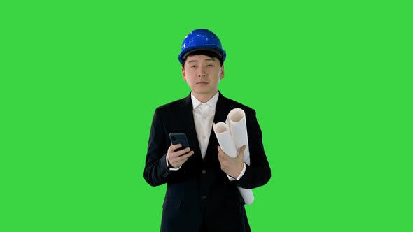 Architect Man Holding Blueprints Using Smartphone and Walking on a Green Screen Chroma Key alt