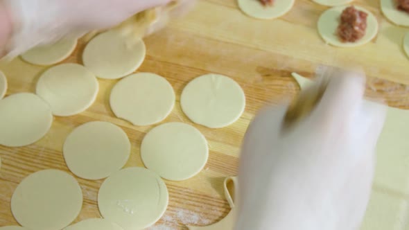 Hands Cut Out Circles of Dough for Making Dumplings in the Production of Semifinished Products