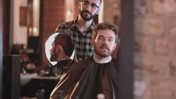 Barber in hairdresser showing client hair cut