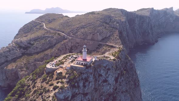 Lighthouse on rocky seashore with curved road alt