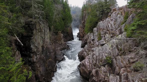 Bubbling stream of a waterfall between rocky shores with forest in Aguasabon Falls, Ontario, Canada alt