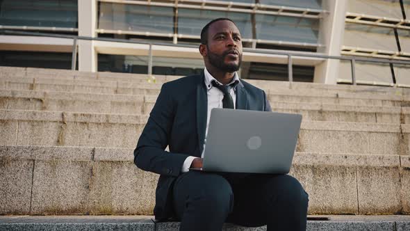 Pensive African American Man Independent Contractor Working on Laptop Outdoor Tracking Shot Slow alt