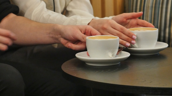 Hands of man and woman holding cups with coffee